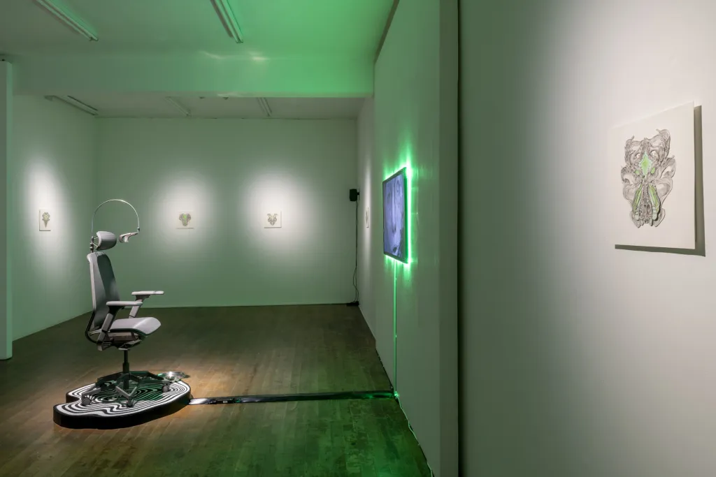 White wall gallery wooden floor green lighting, A gamer chair on a pltform facing a TV, images hang on the surrounding walls. 