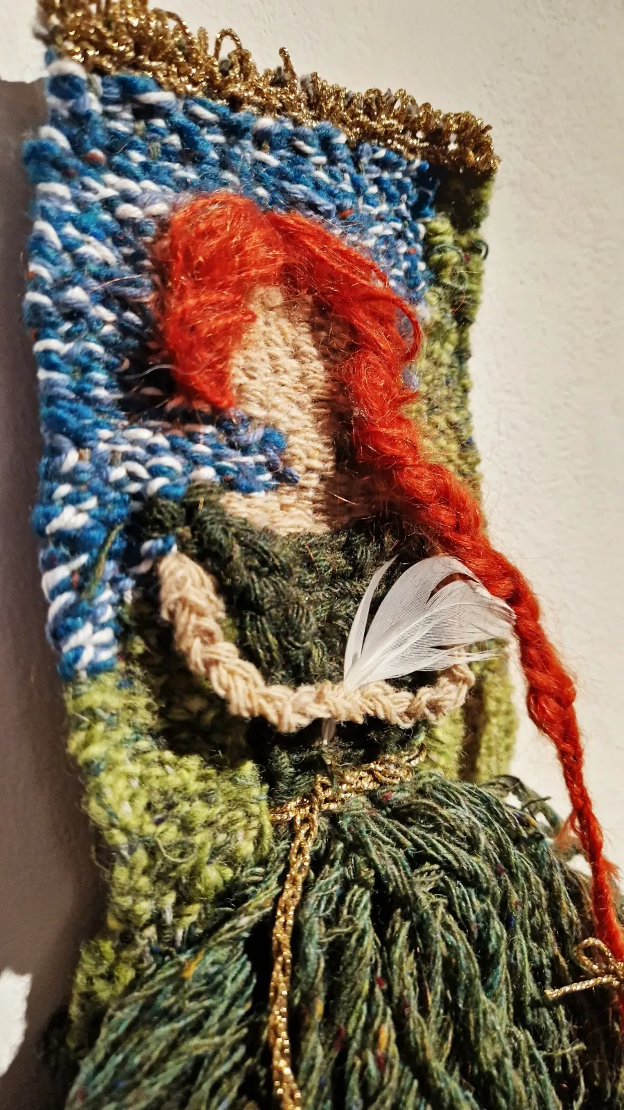 Woven textile piece depicting a woman with long red hair dressed in green.