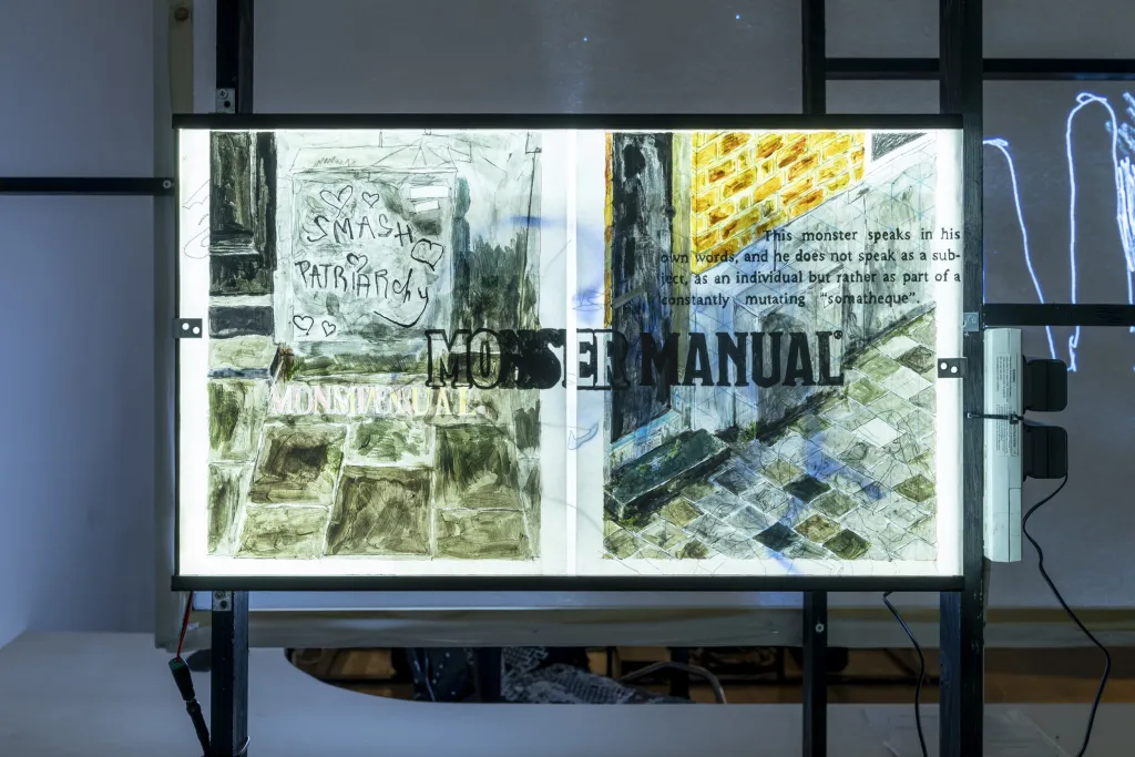 projection screen in an exhibition depicting paintings with text written over them in green, grey and blue tones. 