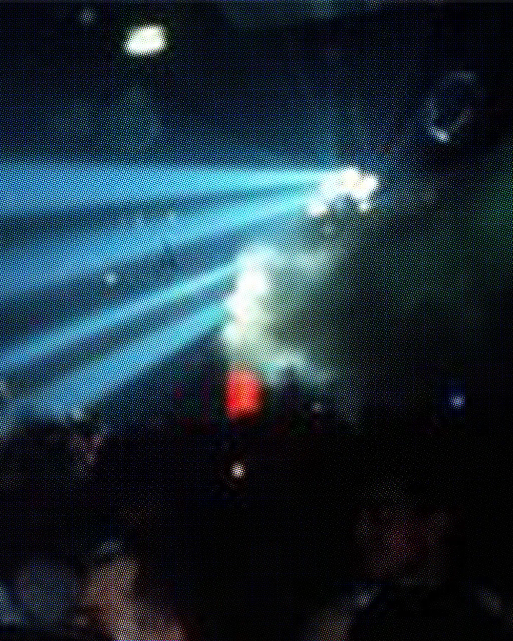 Film photo taken inside a dark nightclub. Blue strobe light shining onto crowded dancefloor.